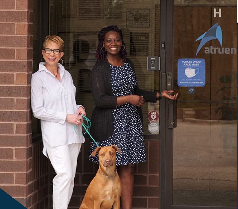 Aida, Alicia, and Winston smiling outside the Atrust office